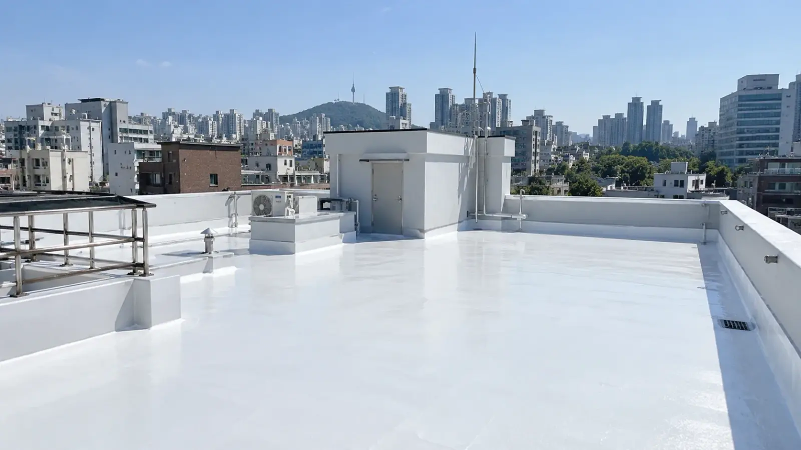 흰색 차열 도료로 쿨루프 시공을 마친 도심 건물 옥상